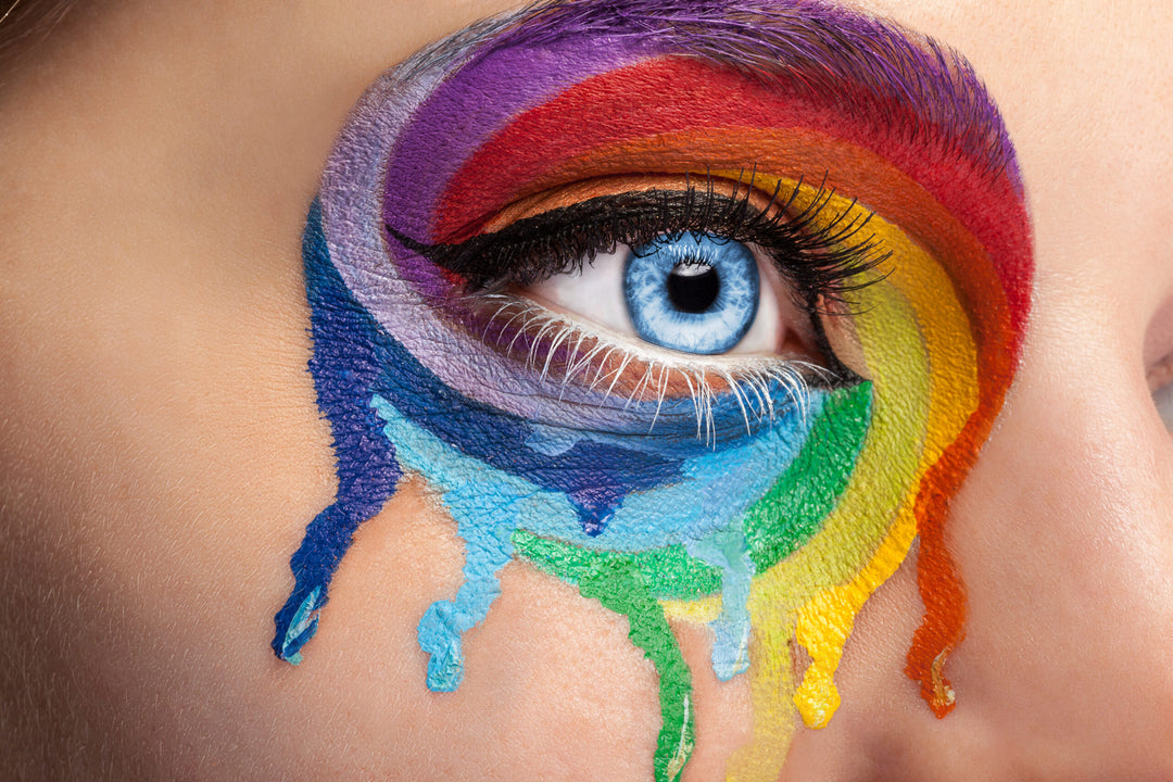 Flowing colors on an eye in fashion stage make up. Rainbow of color spectrum. Blue eye. Close up details. Macro shooting. Fashion on stage make up. Vibrant colors. colored lashes for lgbt pride month